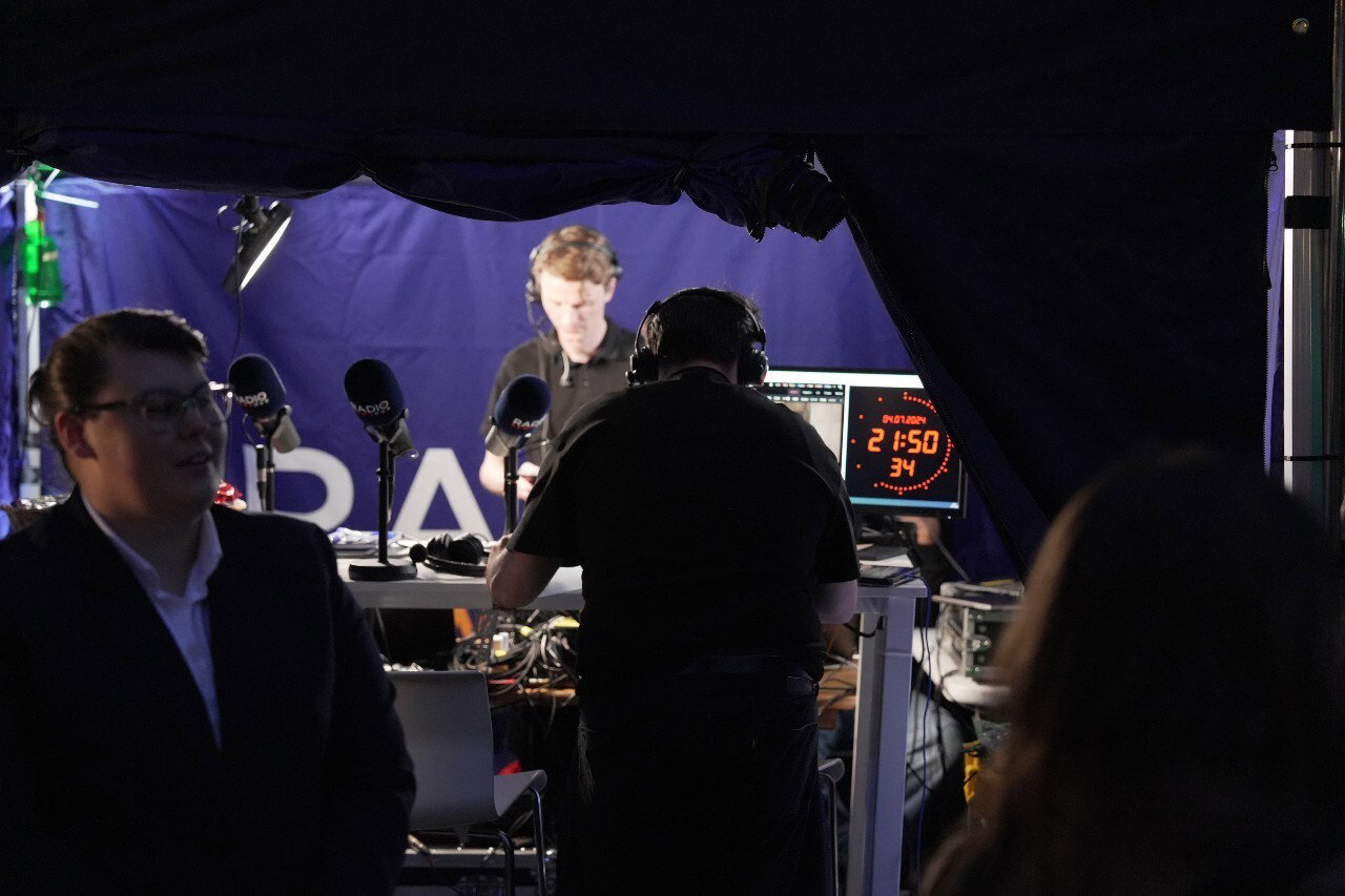 People standing near large microphones.