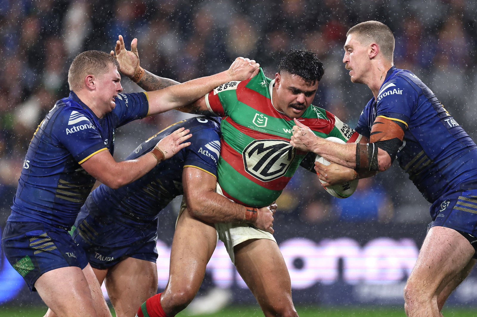 Latrell Mitchell is tackled by Parramatta Eels players in the rain.