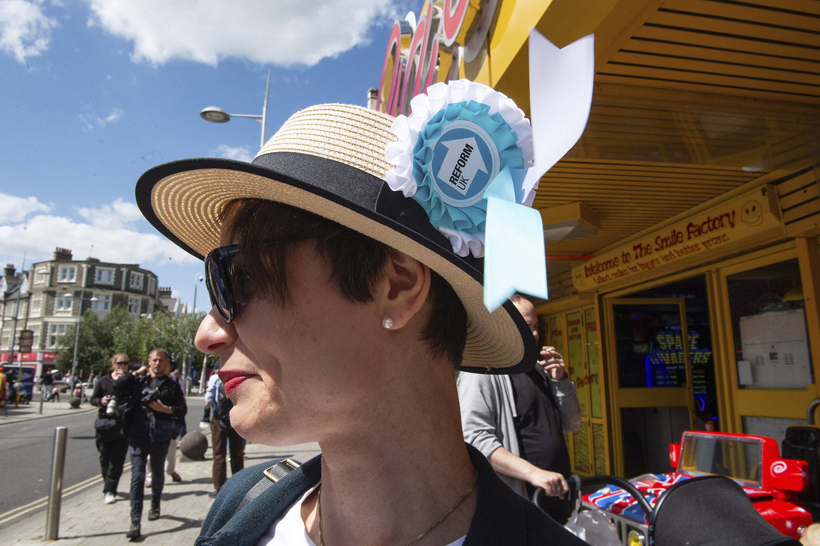 a woman wears a straw hat with a reform rosette